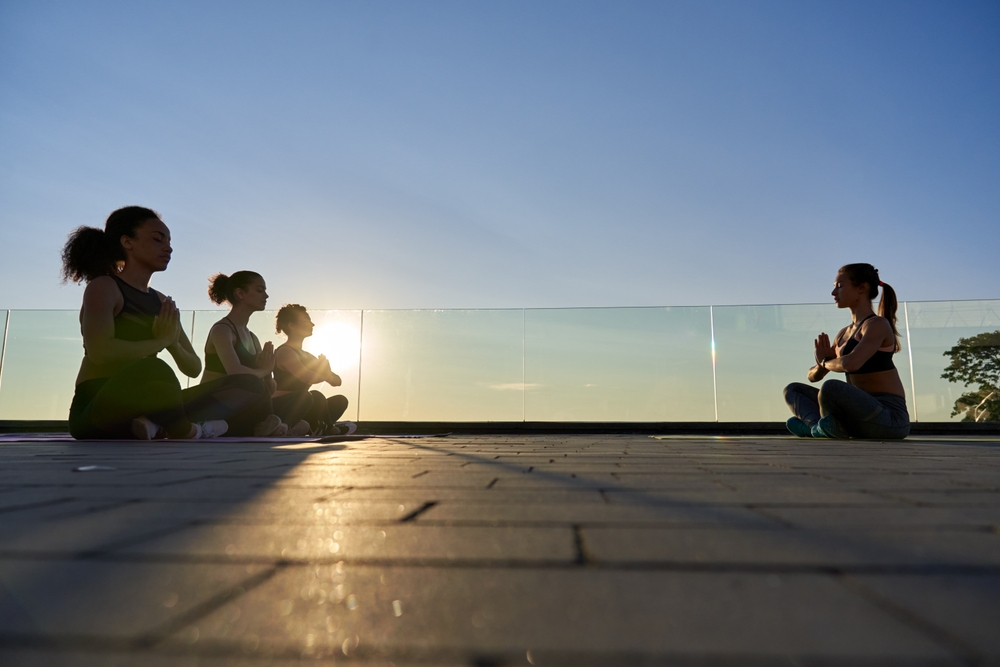 Gruppe von Menschen beim meditieren auf einer Terrasse, bei Sonnenaufgang während des Clarity Retreats
